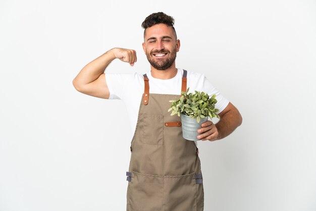 Jardineiro segurando uma planta sobre um fundo branco isolado fazendo um gesto forte