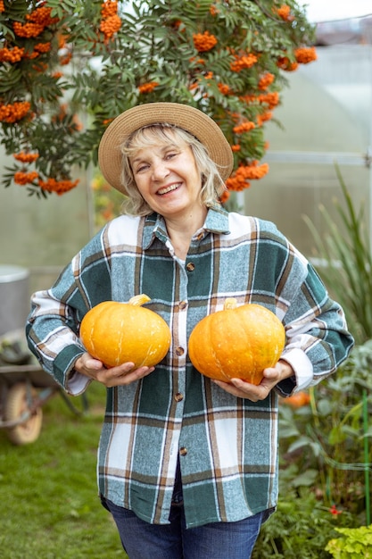 jardinera divertida en su granja sosteniendo calabazas