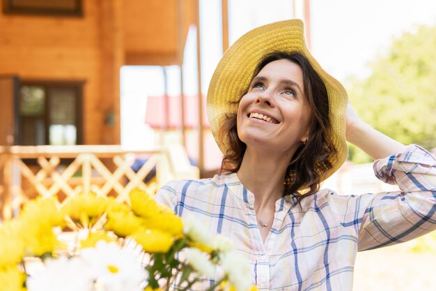 Una jardinera con flores Una mujer con sombrero se dedica a la floristería en el patio de la casa