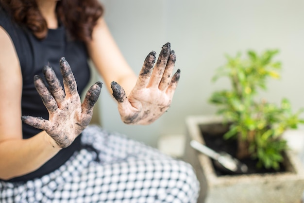 Una jardinera recortada no identificada muestra tierra en las manos sucias mientras planta un árbol en el jardín de su casa. Concepto de tiempo de relajación y hobby.