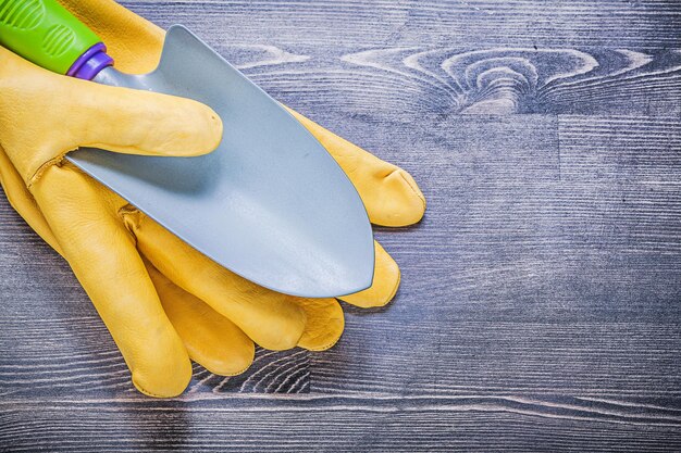 Jardinería guantes de protección mano pala en concepto de agricultura de tablero de madera.