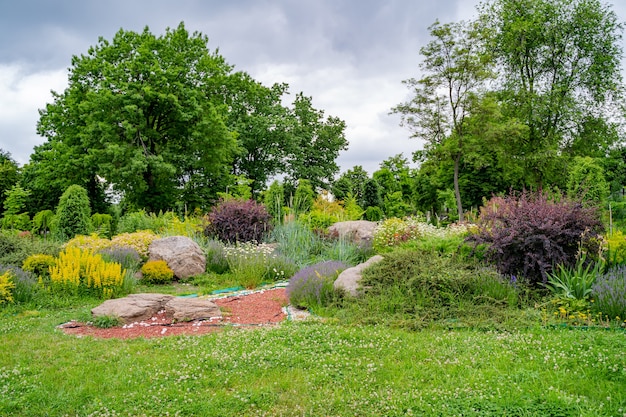 Jardinería paisajística y diseño de paisajismo como un césped de jardín perenne con un macizo de flores y plantas ornamentales en un camino ajardinado decorativo.