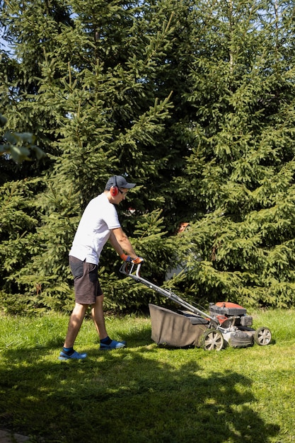 Jardinero cortando el césped con cortadora de césped de gasolina