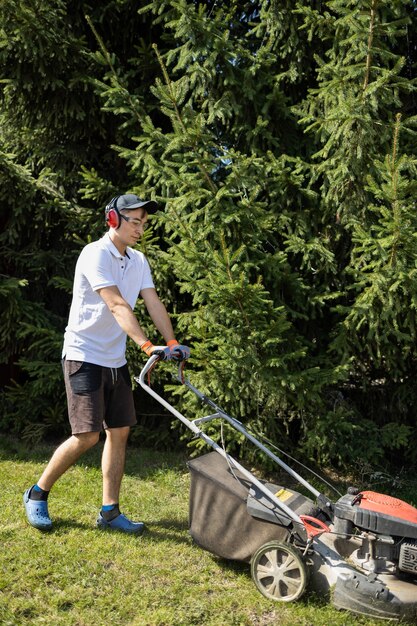 Jardinero cortando el césped con cortadora de césped de gasolina