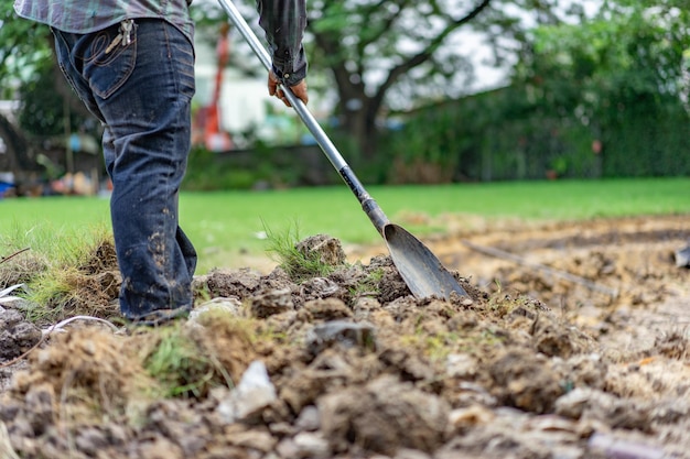 El jardinero excava la tierra con su equipo para la jardinería y prepara la tierra para la plantación.