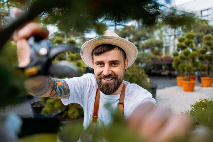 El jardinero feliz está podando arbustos verdes y mirando a la cámara Concepto de herramientas de jardinería