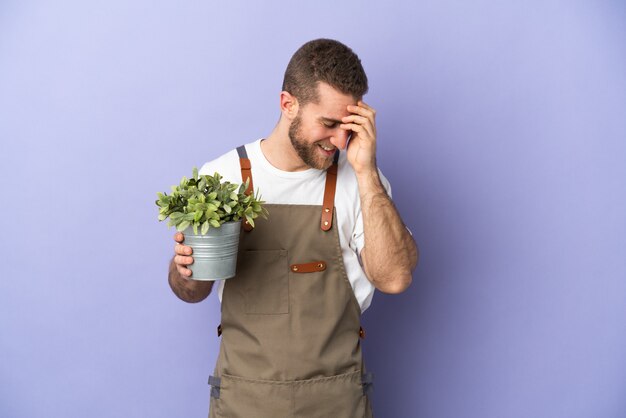 Jardinero hombre caucásico sosteniendo una planta en amarillo riendo