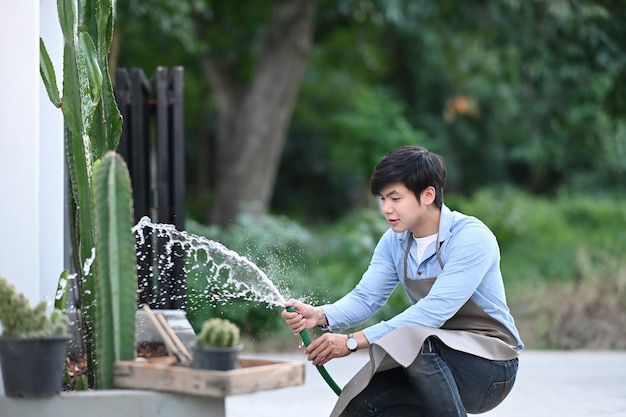 Un jardinero hombre está regando la planta en casa.