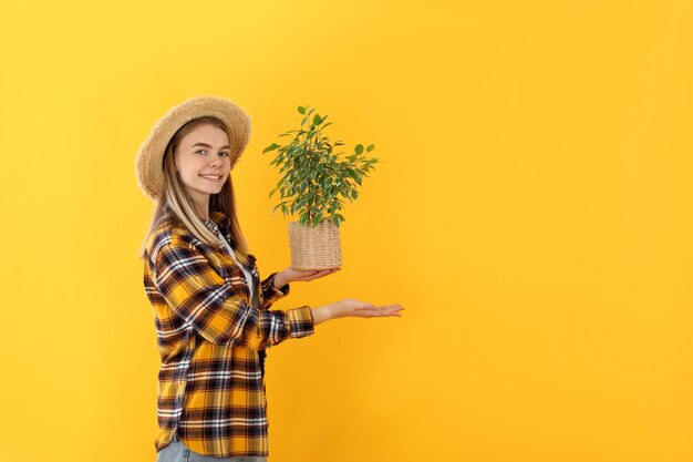 Jardinero joven atractiva sobre fondo amarillo