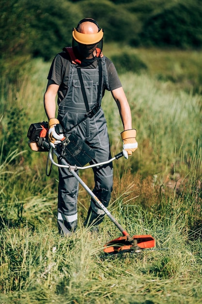 Foto el jardinero masculino corta la hierba con una cortadora de césped.