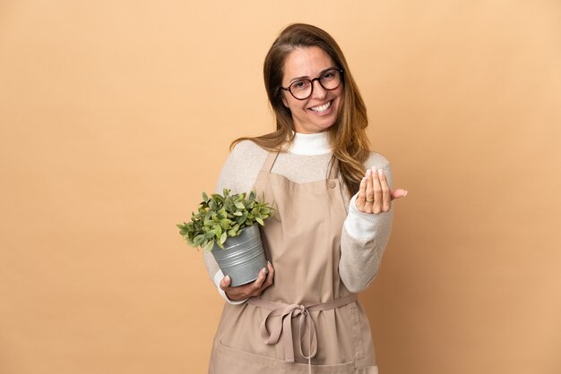 Jardinero de mediana edad mujer sosteniendo una planta aislada