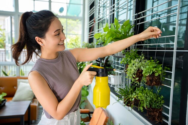 Jardinero de mujer asiática Pulverización de agua sobre la planta en el jardín para un día de relax en casa.