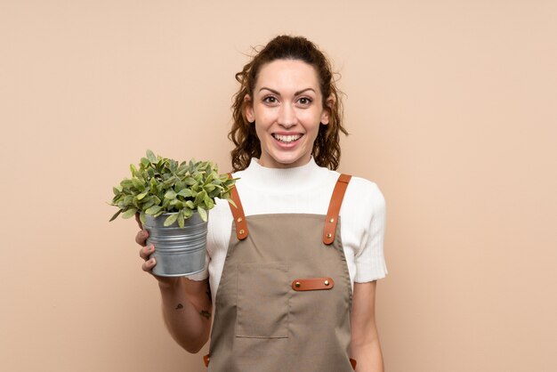 Jardinero mujer sosteniendo una planta con sorpresa y expresión facial conmocionada