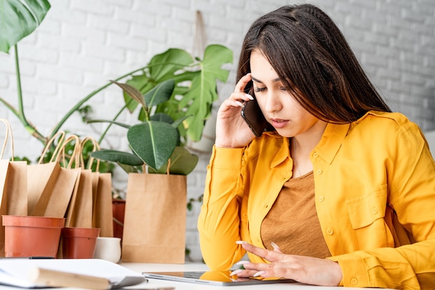 Jardinero de mujer trabajando en tableta digital y llamando por teléfono