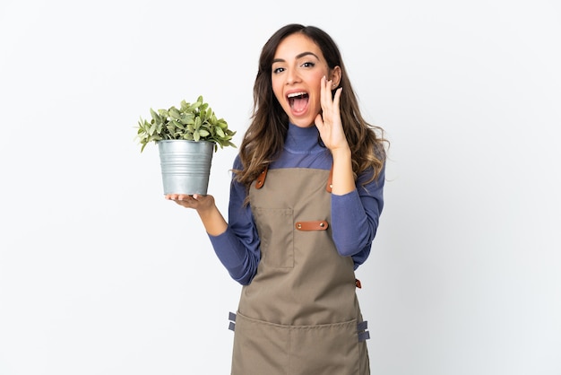 Jardinero niña sosteniendo una planta aislada en el espacio en blanco gritando con la boca abierta