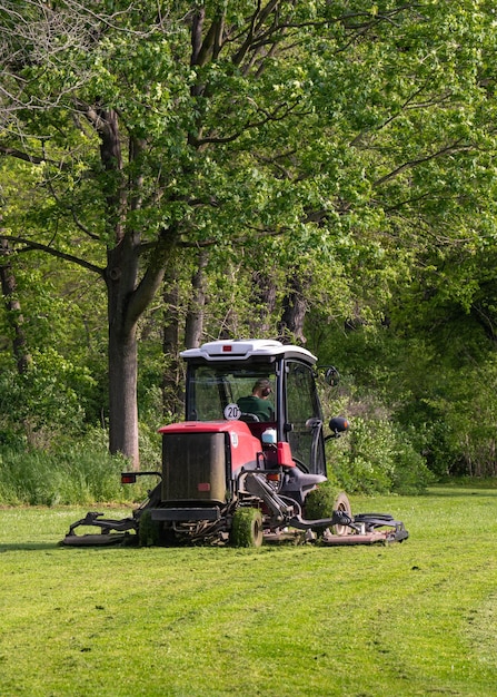 Jardinero profesional cortando hierba verde en una máquina cortadora de césped en el parque Foto de alta calidad