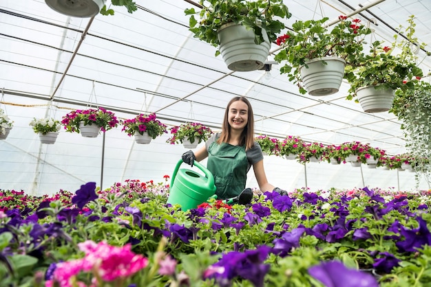 Foto jardinero profesional femenino riego diario y cuidado de flores en un invernadero