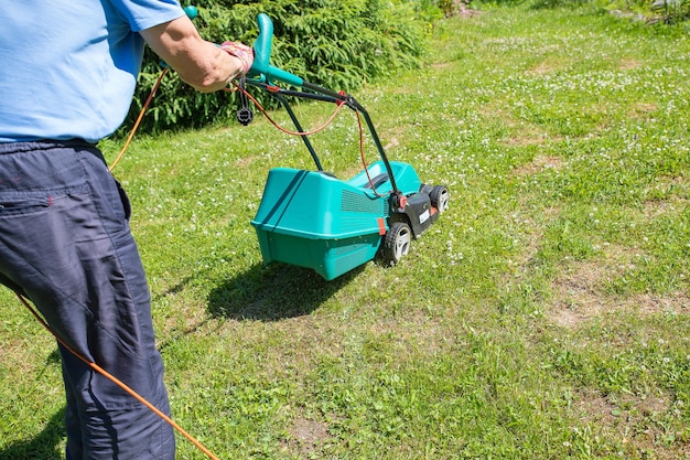 Jardinero senior cortando su césped verde en el jardín Hombre trabajando en el césped cortando hierba con una cortadora de césped el hombre está cortando hierba con una cortadora de césped eléctrica Trabajo físico y trabajo a tiempo parcial