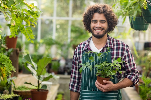 Jardinero de sexo masculino sonriente que sostiene la planta en maceta