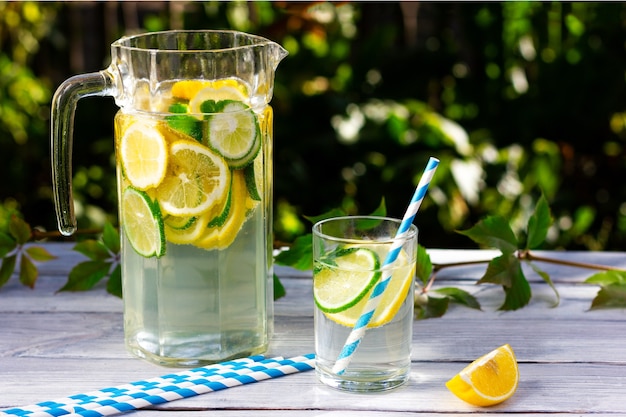 Una jarra de agua fría con rodajas de limón y lima sobre una mesa de madera clara