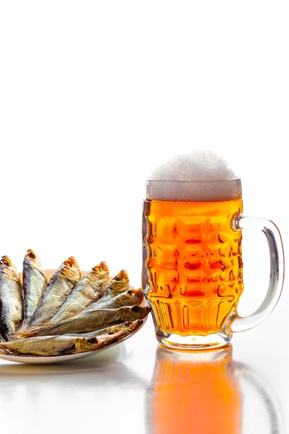 Jarra de cerveza ligera con aperitivo de pescado seco en un plato blanco