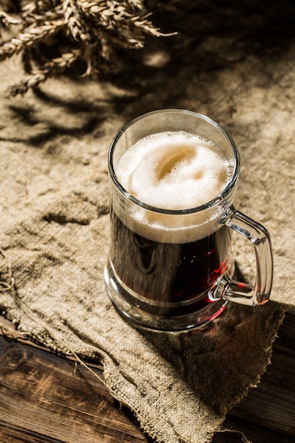 Jarra de cerveza con trigo sobre lienzo.