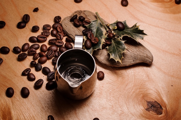 Jarra com água entre os grãos de café frescos e plantas secas