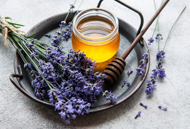 Jarra com mel e flores frescas de lavanda em um fundo de concreto