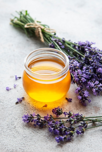 Jarra com mel e flores frescas de lavanda em um fundo de concreto