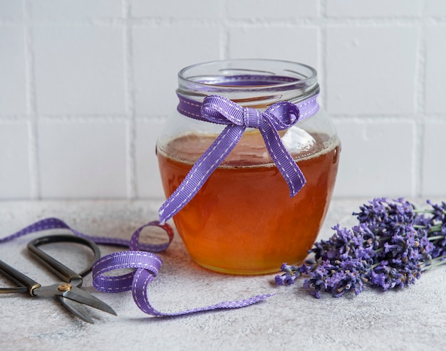 Jarra com mel e flores frescas de lavanda em um fundo de concreto