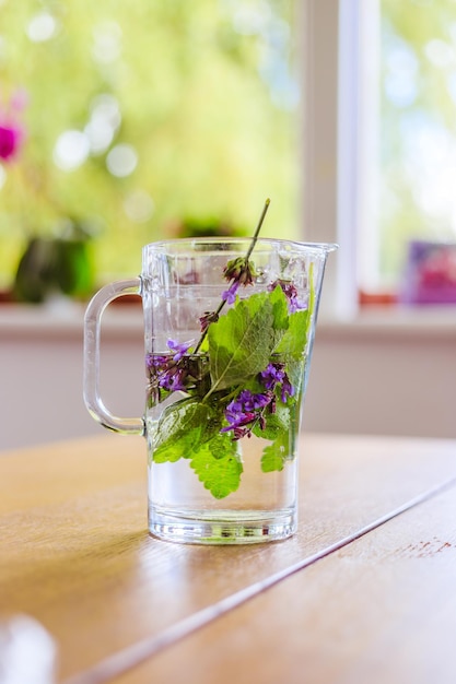 Jarra de água fria e refrescante no verão Saborosa limonada com ervas multicoloridas