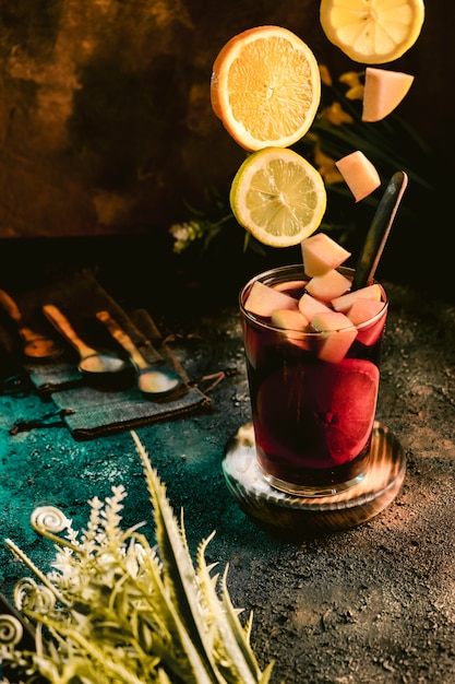 Jarra de sangria fria com frutas em uma superfície escura