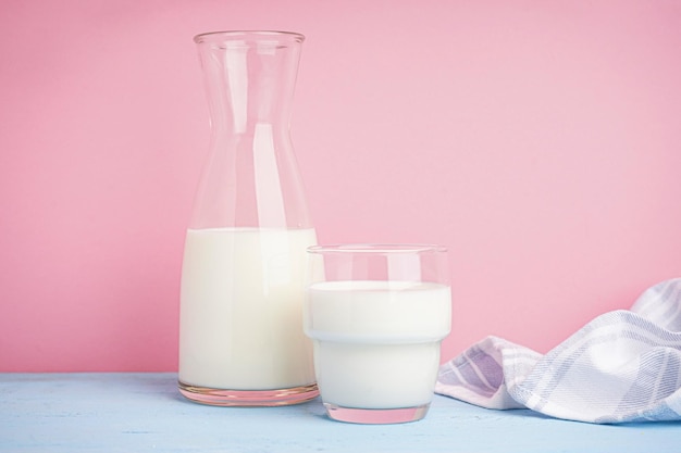 Foto jarra e copo de leite fresco em fundo rosa claro