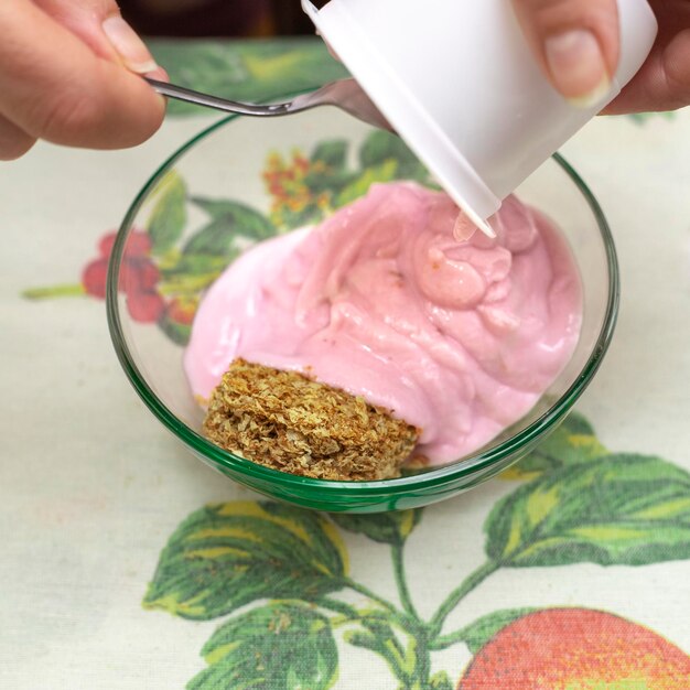 Foto una jarra con granola de yogur vertida en un cuenco transparente