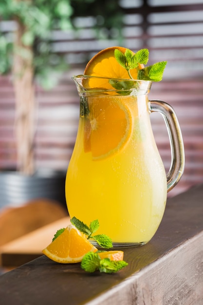 Una jarra de jugo de naranja natural con una rodaja de limón y menta.