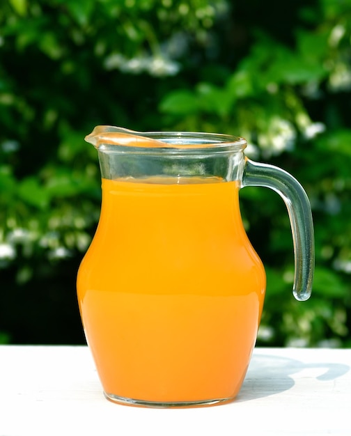 Foto jarra de jugo de naranja sobre mesa de madera sobre fondo verde