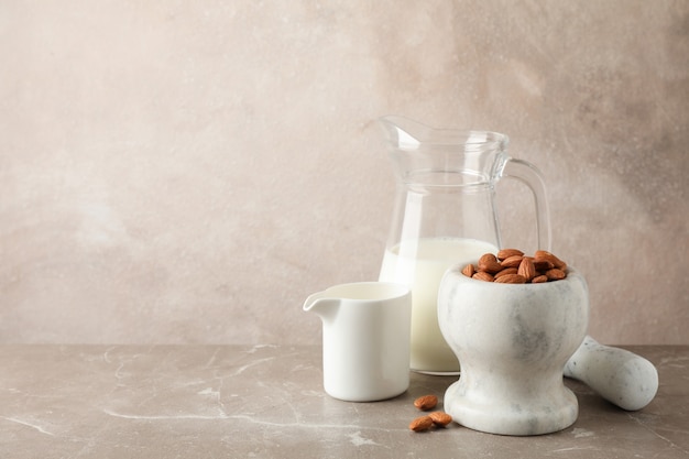Jarra de leche de almendras, mortero con semillas de almendras en mesa marrón