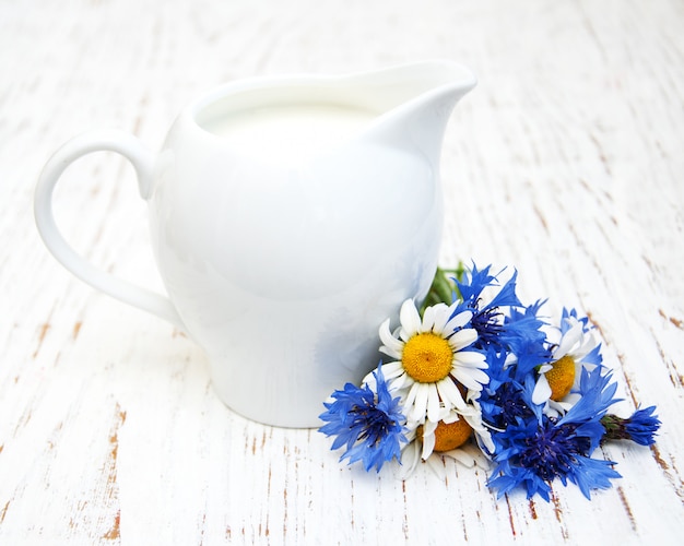 Jarra de leche y flores silvestres.