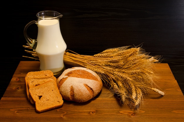 Jarra de leche, pan de centeno y una gavilla