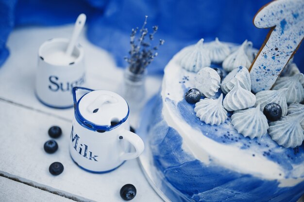 Jarra de leche y tarta sobre un fondo azul junto a un jarrón con ramas de lavanda