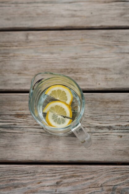 Jarra de limonada con limón sobre mesa de madera. vista superior. una bebida para saciar la sed