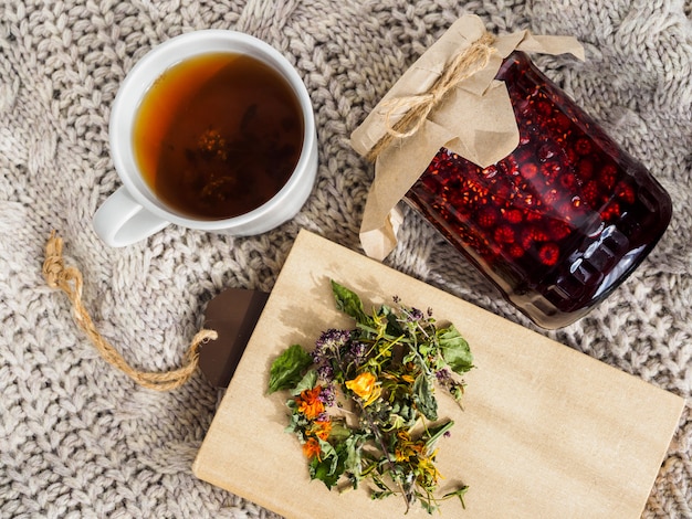 Una jarra de mermelada de frambuesa y una taza de té caliente.