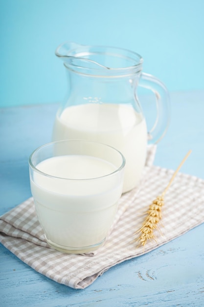 Jarra y vaso de leche fresca sobre fondo de madera azul claro