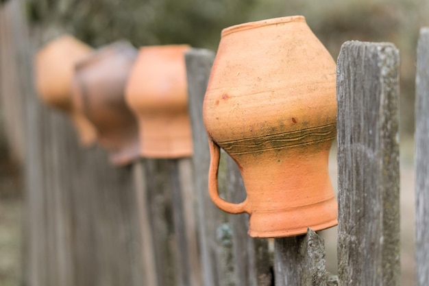 Jarras de arcilla marrón colgando de una valla de madera en Ucrania Decoración rural vintage tradicional