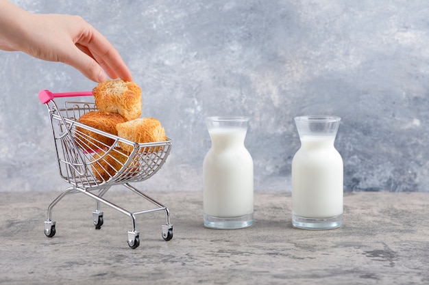 Jarras de vidrio de leche fresca con deliciosas galletas colocadas sobre un fondo de mármol.