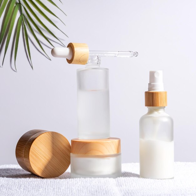 Jarro de crema de bambú y botella de gotero con aceite facial sobre un fondo blanco Maquetas de envases cosméticos Fondo para la presentación de marcas y envases Concepto de producto de belleza natural para el cuidado de la piel