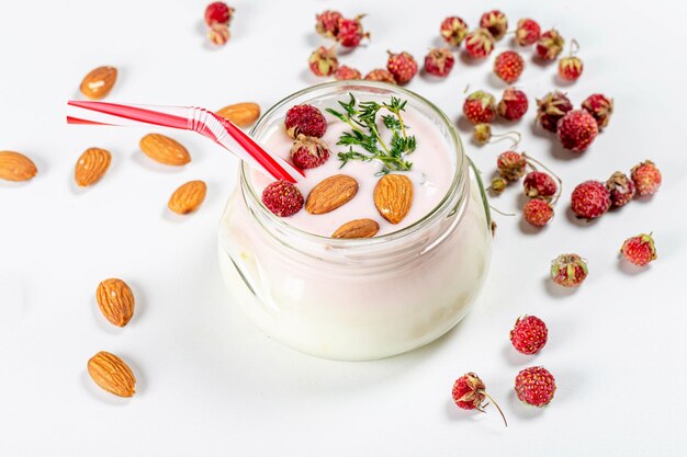 Foto jarro de vidro com iogurte, morangos e amêndoas conceito de pequeno-almoço saudável