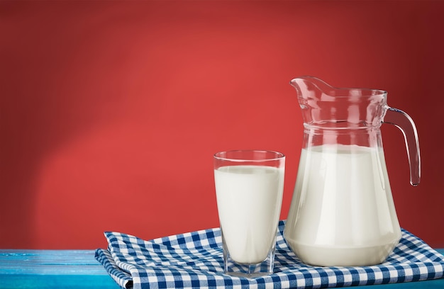 Jarro e copo com leite em mesa de madeira