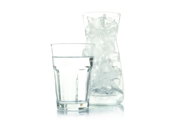 Jarro con hielo y un vaso de agua aislado sobre un fondo blanco