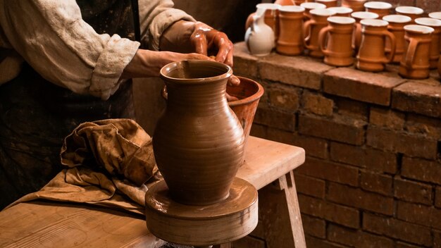 Jarrón de arcilla y manos de alfarero trabajando en arcilla